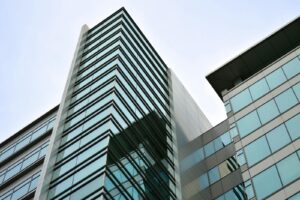 Vue en contre-plongée d'un gratte-ciel moderne avec une façade en verre reflétant le ciel.